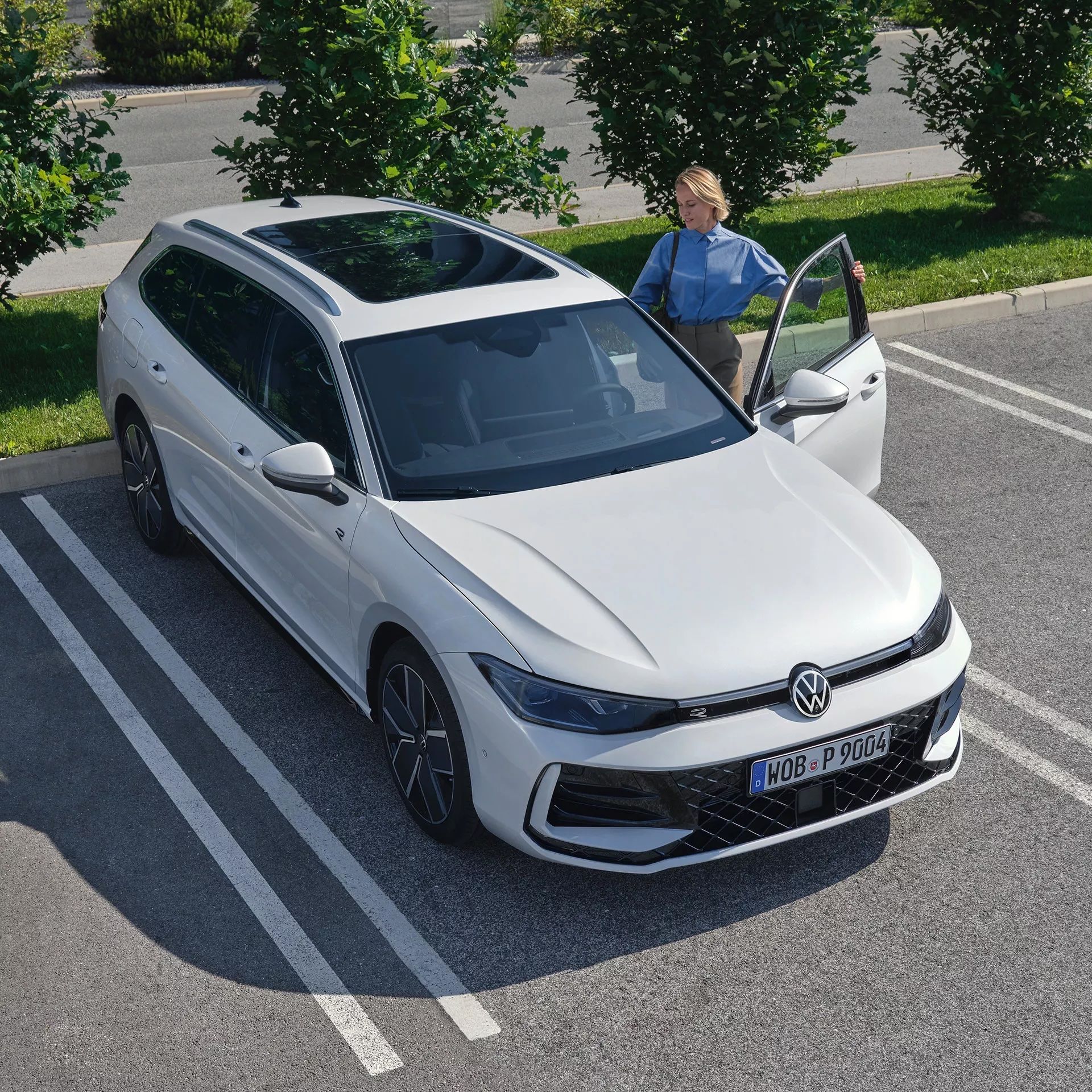 Der neue Passat Topshot eines neuen weißen VW Passat auf einem Parkplatz, eine Frau steigt auf der Fahrerseite ein.