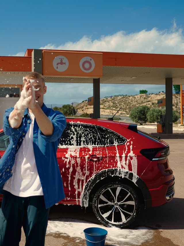 VW Taigo VW Taigo Style Front- und Seitenansicht in Grün auf Parkplatz vor pinkem Gebäude